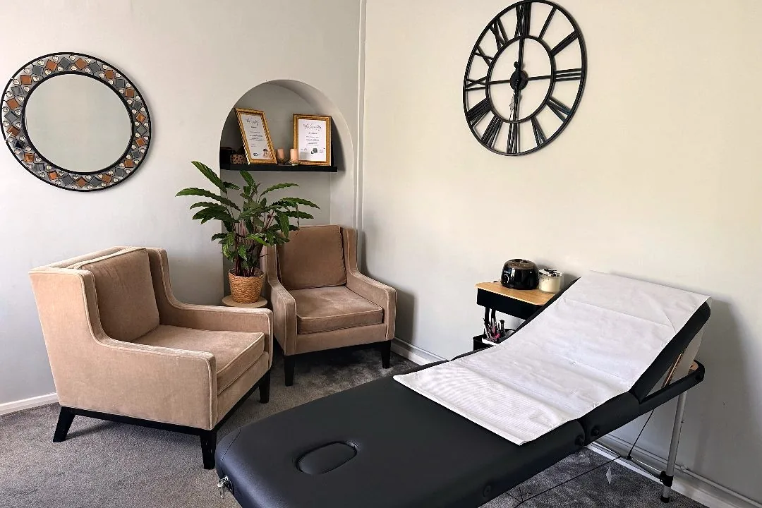 Bright treatment room with velvet armchairs and a lash bed